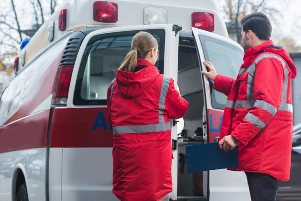 mannelijke en vrouwelijke paramedici ambulance deuren sluiten - Foto, afbeelding