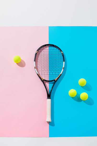 κάτοψη του ρακέτα του τένις και κίτρινες μπάλες για μπλε και ροζ έγγραφα - Φωτογραφία, εικόνα