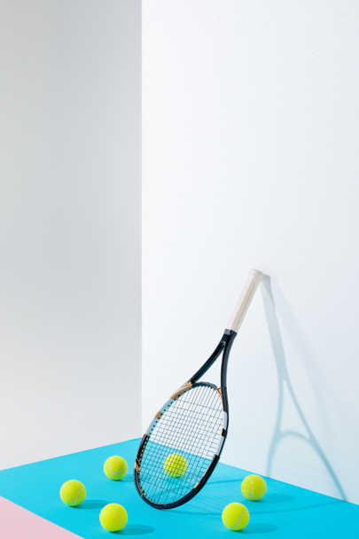 circle of tennis balls on blue around tennis racket at white wall with copy space - Foto, imagen