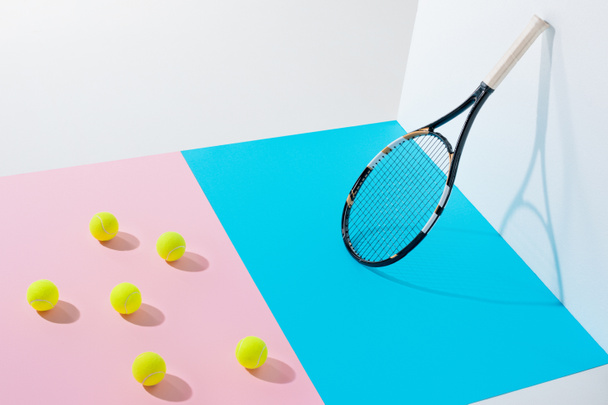 yellow tennis balls on pink paper and tennis racket on blue at white wall - Fotoğraf, Görsel
