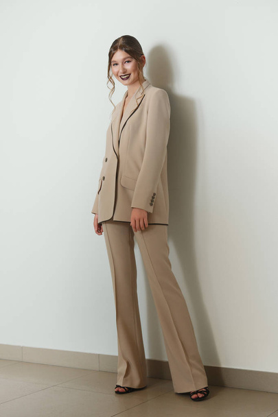 Aantrekkelijke model in beige jas en broek suite - Foto, afbeelding