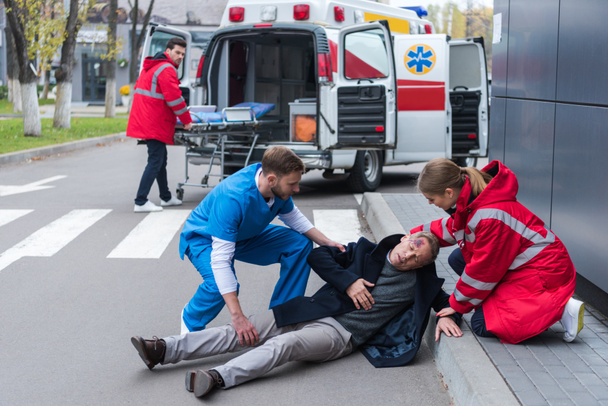 medici che aiutano l'uomo ferito sdraiato su una strada
 - Foto, immagini