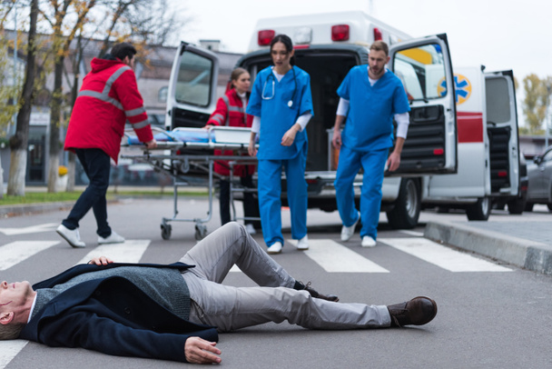 rajattu kuva lääkäreistä menossa haavoittunut keski-ikäinen mies makaa kadulla
  - Valokuva, kuva