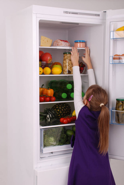 Hermosa chica cerca del refrigerador con comida saludable
.  - Foto, Imagen