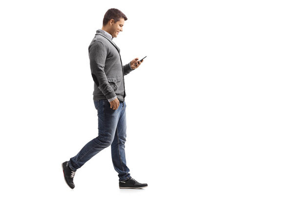 Young man walking and using a phone - Fotó, kép