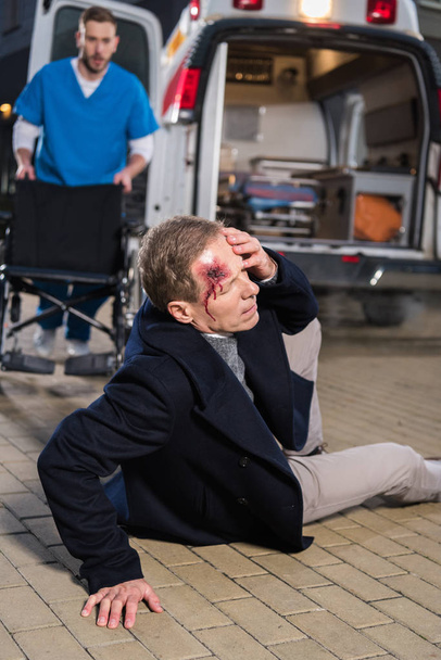 médico va a ayudar a hombre herido acostado en una calle
 - Foto, Imagen