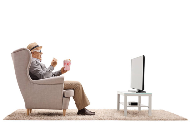 мужчина в 3D очках в кресле ест попкорн
 - Фото, изображение