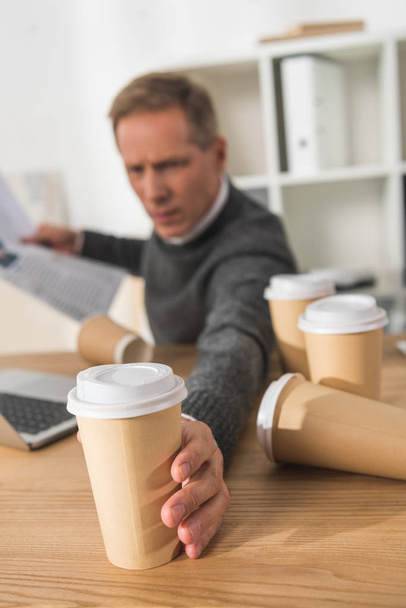cansado hombre de negocios de mediana edad tomando una taza de café desechable más
 - Foto, Imagen