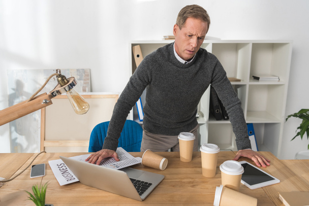 mature man feeling bad and leaning on table in office - Photo, Image