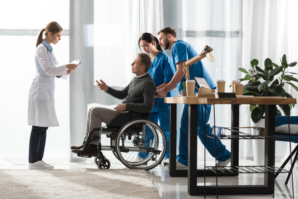 lekarka rozmawia z bliskiego wieku pacjenta, na wózku inwalidzkim  - Zdjęcie, obraz