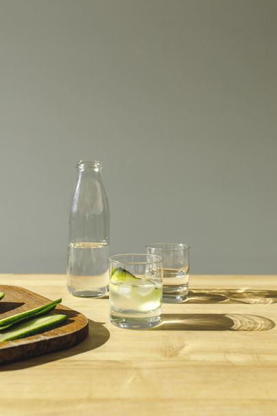 cut cucumbers and mineral detox water on wooden tabletop  - Photo, Image