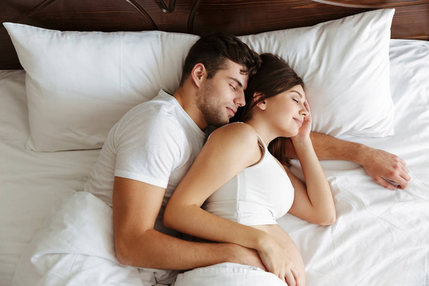 Pregnant woman sleeping in bed with her husband - Фото, зображення
