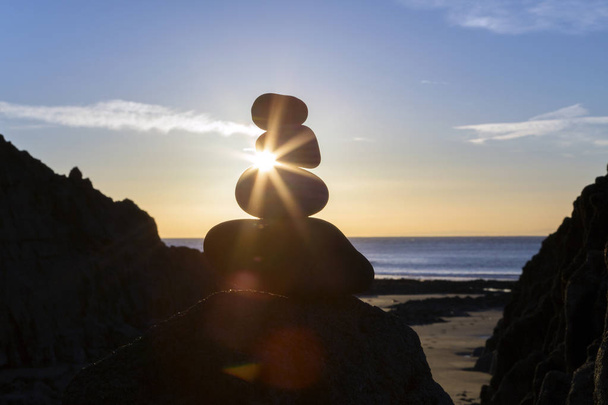 サンバーストと海の背景が付いている浜の石杭 - 写真・画像