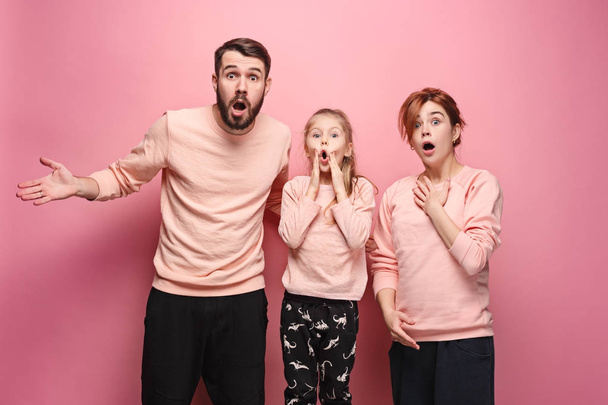 Surprised young family looking at camera on pink - Foto, Imagen