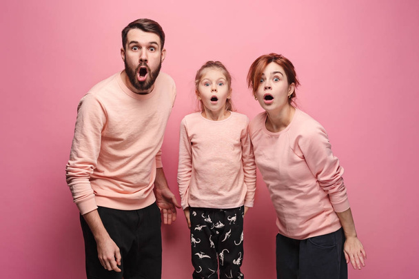 Surprised young family looking at camera on pink - Foto, Imagem