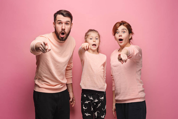 Surprised young family looking at camera on pink - Photo, Image