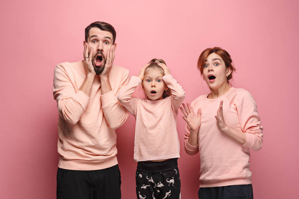 Surprised young family looking at camera on pink - Фото, зображення