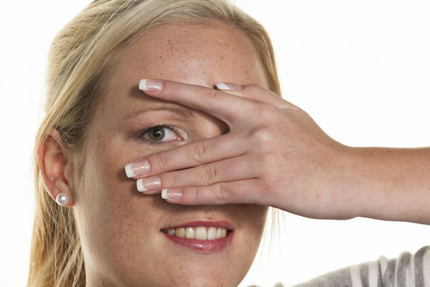 woman looks through fingers of her hand - Photo, image