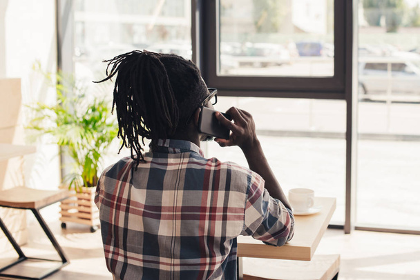 rear view of african american man talking on smartphone in cafe - Zdjęcie, obraz