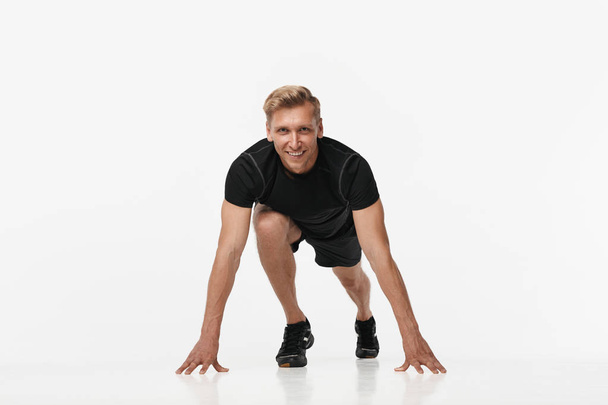 Smiling sportsman in crouch start on white - Foto, Imagem