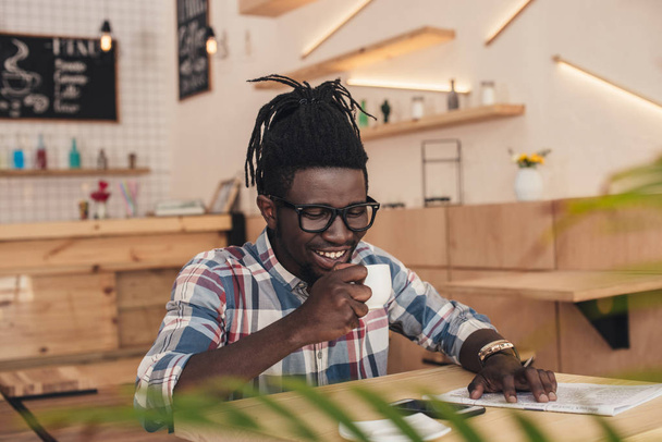 cheerful african american man drinking aromatic coffee in cafe - Foto, Imagem