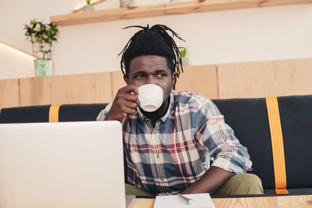 カフェでコーヒーを飲んでラップトップにアフリカ系アメリカ人 - 写真・画像