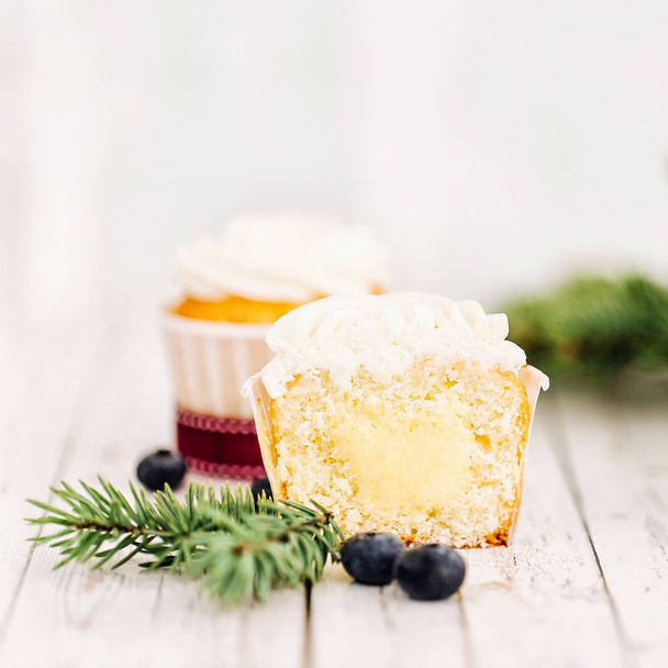 delicioso cupcake dulce y ramita de abeto sobre mesa de madera blanca
  - Foto, Imagen