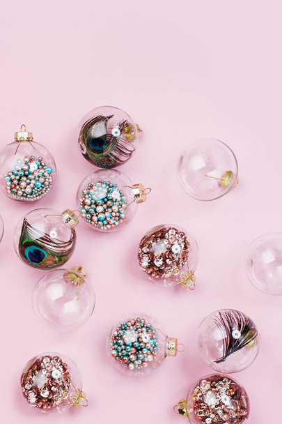 beatiful glass christmas balls with beads and peacock feathers inside on pink background  - Fotografie, Obrázek