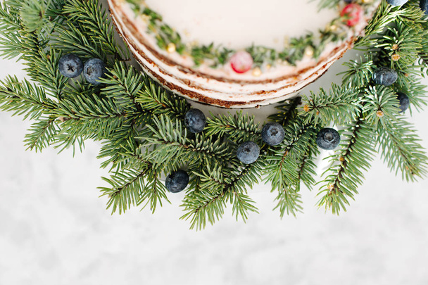 Christmas cake decorated fir branches and berries, close up - Fotó, kép