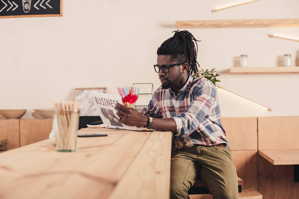 african american man reading business newspaper while sitting at bar counter  - Foto, immagini