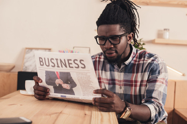 concentrated african american man reading business newspaper in cafe - Photo, Image