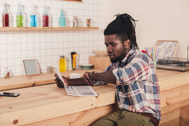 homem americano africano sentado no balcão de bar e lendo jornal de negócios
 - Foto, Imagem