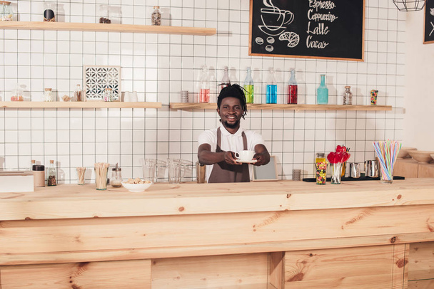 Afro-Amerikan barista kahve fincanı bar sayacı, dururken tutan önlük - Fotoğraf, Görsel