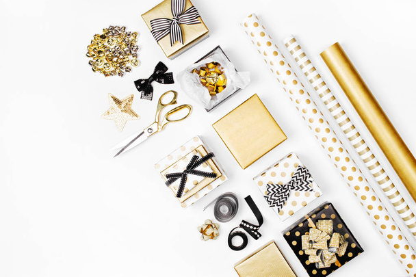 flat lay of golden presents, wrapping paper and decorations on white background  - 写真・画像