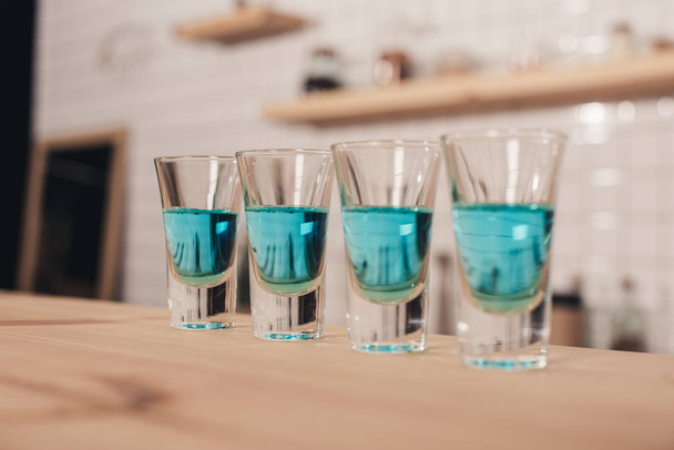 close up of blue cocktails in shot glasses standing on bar counter - Foto, Bild