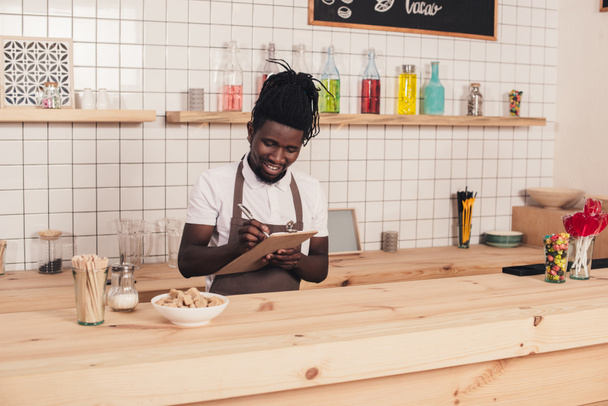 souriant afro-américain barista prendre commande au comptoir bar
 - Photo, image