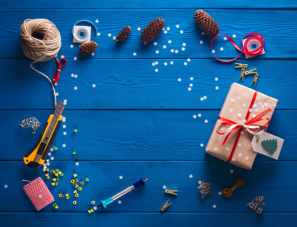 scrapbooking. Packing a Christmas gift in kraft paper on a blue wooden background - Fotografie, Obrázek