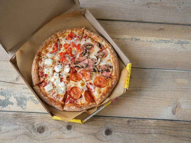 Pizza in delivery box on wooden table - Fotó, kép
