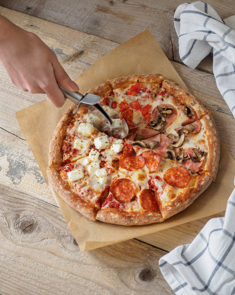 Domácí pizza nastavena na papíře na dřevěný stůl - Fotografie, Obrázek