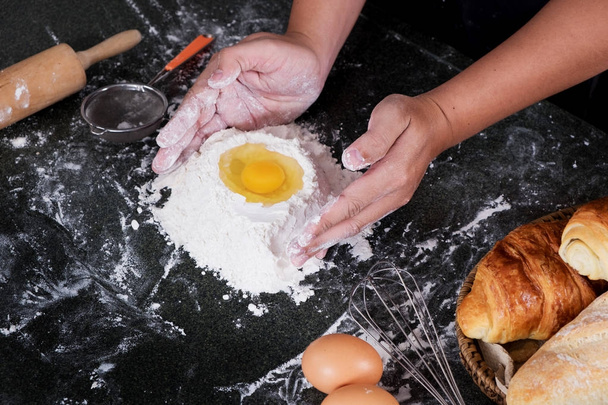 Женские руки месят тесто с мукой, яйцами и ингредиентами. at k
 - Фото, изображение