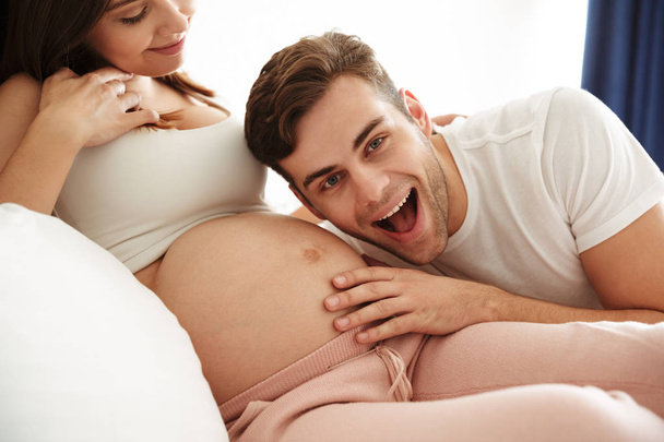 Happy young man listening his pregnant wife's belly - Fotoğraf, Görsel