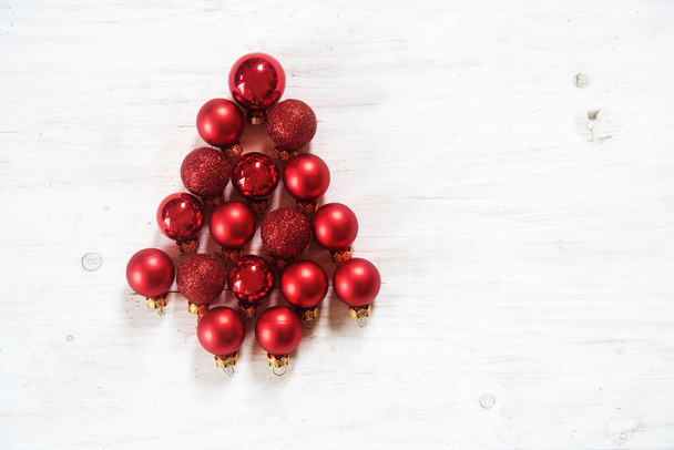 red Christmas balls in the shape of a fir tree on white painted rustic wood, christmas background or greeting card, flat top view from above, copy space - Fotoğraf, Görsel