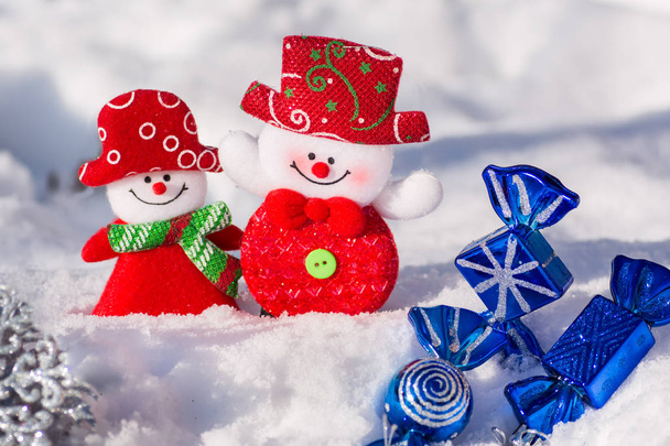 青いキャンディーと銀色のスノーフレーク クリスマスおもちゃで雪の中で陽気な雪だるまのペア。メリー クリスマスと新年あけましておめでとうございます! - 写真・画像