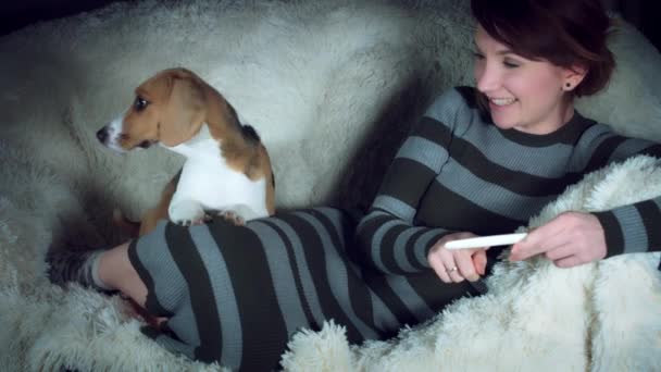 Mujer embarazada comprobando el resultado de la prueba de embarazo, acostada en un sofá con un lindo perro
 - Imágenes, Vídeo