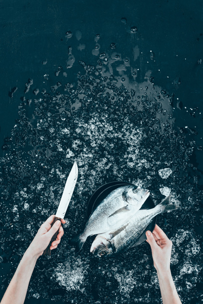 cropped shot of human hands with knife and fresh dorado fish on black - Фото, зображення