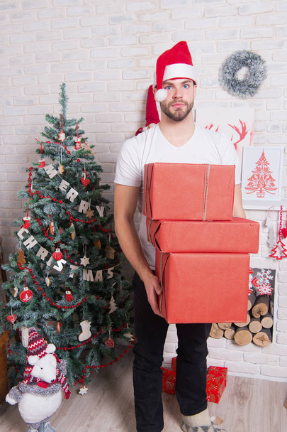 Macho in red hat hold wrapped presents - Zdjęcie, obraz