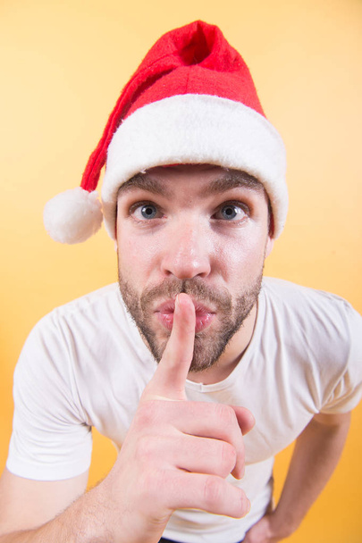 Guy put finger to mouth in red santa hat - Foto, Imagen