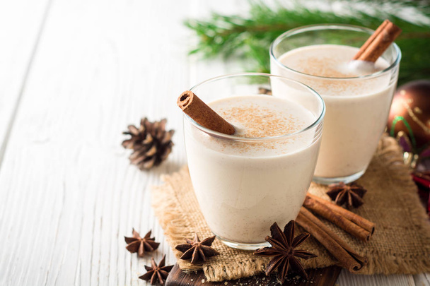 Homemade eggnog with grated nutmeg and cinnamon on white wooden table. Traditional Christmas drink. - Фото, изображение