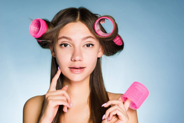 attractive young girl wants a beautiful hairstyle, on her head big pink hair curlers - Φωτογραφία, εικόνα