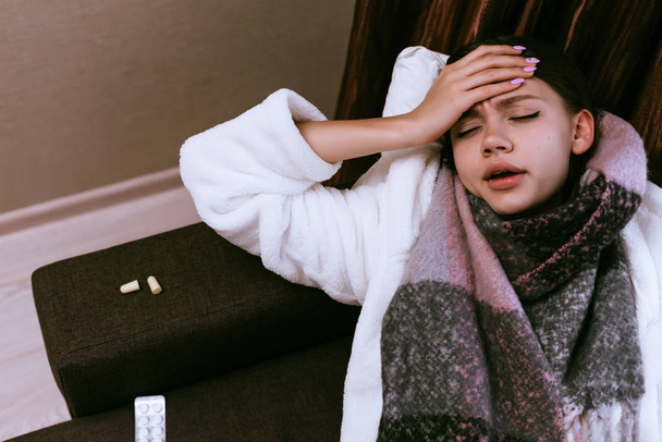 sad young girl gets sick, headache and heat, neck warm scarf - Fotó, kép